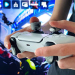 Person holding a gaming controller with a blurred game interface in the background with IMP Tech Trigger Treadz Combat Elite Trigger Grips + Thumb Grips - Urban Camo for PlayStation 5 controllers.