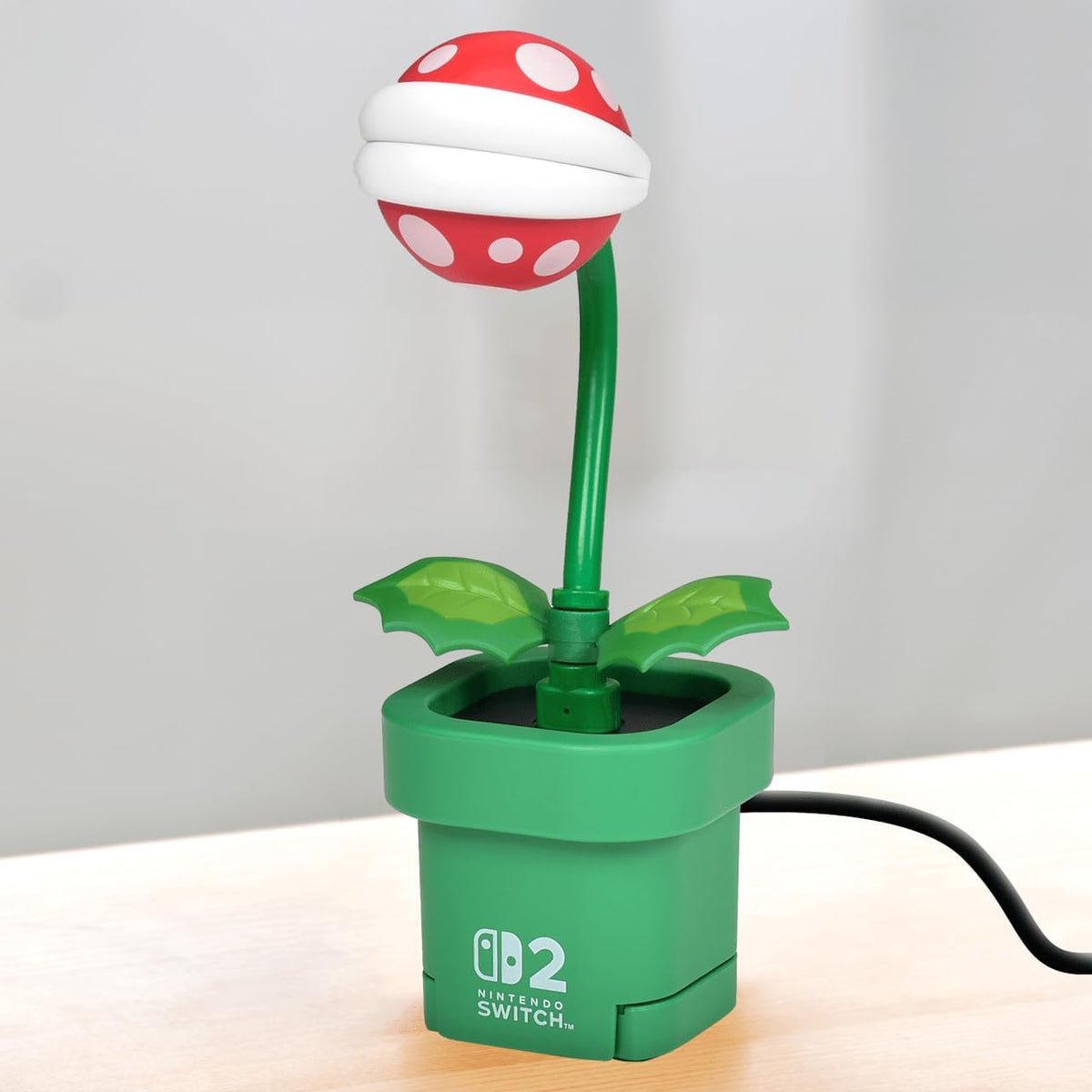 Side view of the HORI Piranha Plant Camera for Nintendo Switch 2, featuring the adjustable plant stem, green leaves, red and white head and Warp Pipe base.