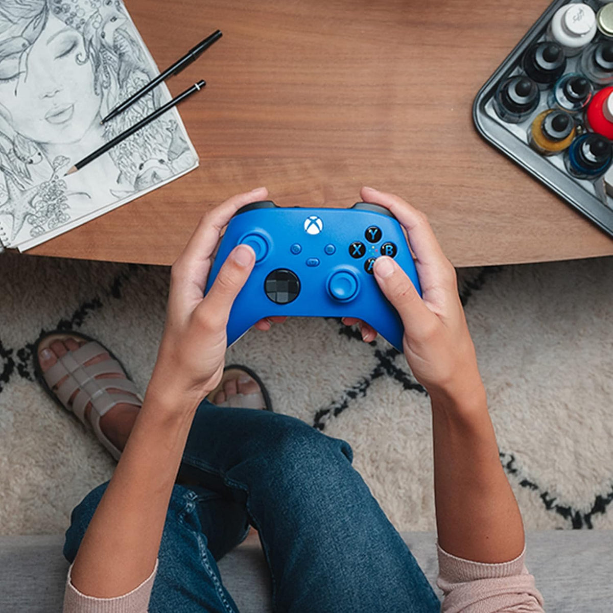 Microsoft Xbox Wireless Controller in Shock Blue held in both hands during gaming, showing its comfortable ergonomic shape and distinctive blue design.