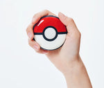 Pokémon GO Plus + device held in one hand, showing its compact Poké Ball design and central button for interacting with Pokémon GO and Pokémon Sleep.