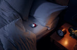 Pokémon GO Plus + promotional image showing the device being used beside a bed at night, illustrating its Pokémon Sleep tracking functionality.