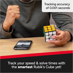 Person holding a Rubik's Cube ConnectedX beside a smartphone on a wooden table